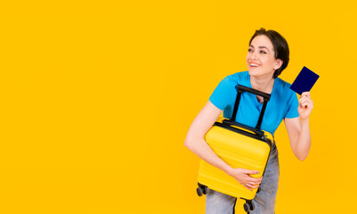 joyful woman in blue t-shirt with yellow suitcase and passport on yellow background. Travel enjoy concept