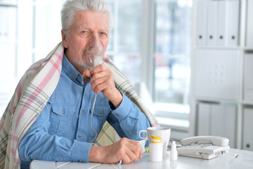 Sick elderly man makes inhalation