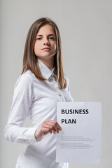 Business plan displayed, white shirt, brown-haired woman