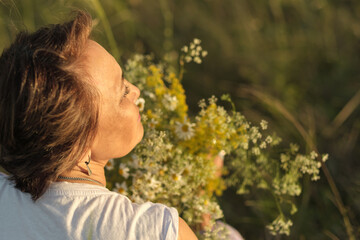 thoughtful, modern retiree immerses herself in tranquility of summer meadow, wildflowers in her...