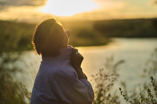 thoughtful, modern retiree immerses herself in tranquility of summer meadow, wildflowers in her hands serving as poignant reminder of life's continuous journey and her own resilience through life