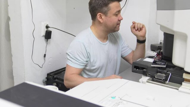 operator in darkroom sets up printer for perfect printed copies of photos