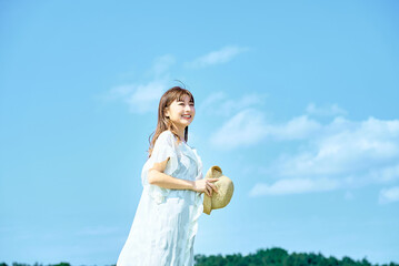 快晴の空の下でリラックスした表情を見せる若い女性