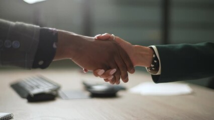 Closeup side view of handshaking for unrecognizable African businessman and Caucasian woman which was just finished or success business deal on working desk shows professional concept of sex equality.