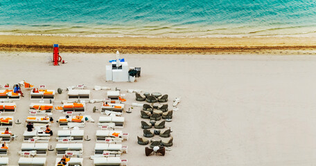 Birds eye view over beach with lounge chairs and umbrellas by the ocean. aerial view.
