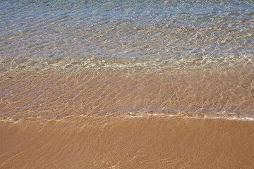 Sea background, nature of tropical summer beach with rays of sun light. Sand beach, sea water with copy space, summer vacation concept.