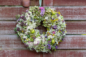 Wiesenblumen-Kranz hängend an der Holz-Gartentür
