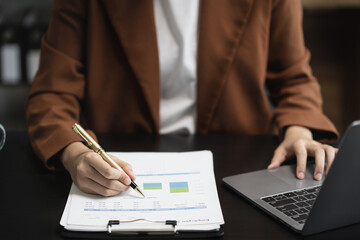 Female writes information businessman working on laptop computer writing business plan while sitting in office.