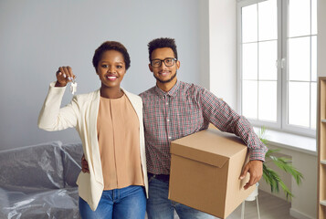 Portrait of happy ethnic couple buyers hold keys to new house, buy dwelling moving together. Smiling multiethnic man and woman clients celebrate relocation to own home. Rental, real estate concept.