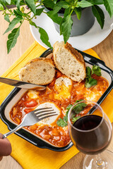 Traditional oriental cuisine. Arabic dish Shakshuka. Turkish breakfast, fried eggs, tomato sauce, peppers, cilantro and 2 pieces of baguette.