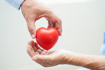 Asian woman doctor holding red heart for health in hospital.