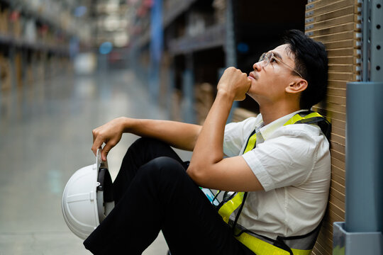 An Asian warehouse worker who is tired from work. Getting fired from a job. Unemployed. Failed. Desperate.