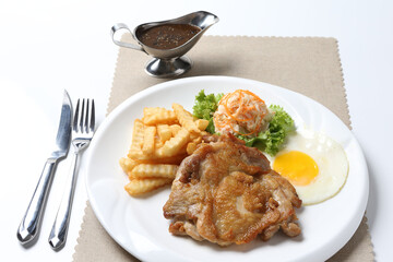 grilled golden bbq chicken chop pork cutlet beef steak with fried egg, French fries, coleslaw salad and black pepper sauce on brown leather white background western chef halal food restaurant menu
