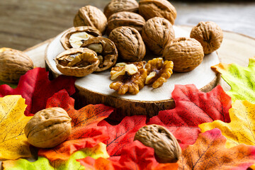 Close up shot of Group of walnuts on a natural wooden tray and some colorful autumn leaves