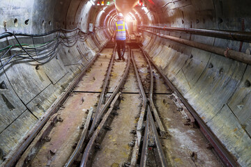 Fototapeta na wymiar Rail way with lighting background and engineer or technician control. Underground tunnel infrastructure. Transport pipeline by Tunnel Boring Machine for electric train subway