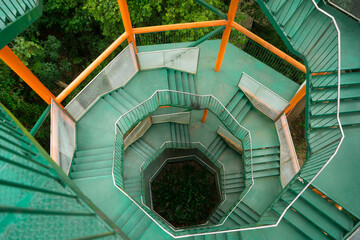 Spiral staircase that made from steel use to climb up the tower to see view or survey route that around with tree background.