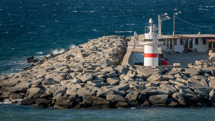 Aerial view of the Lighthouse and fishermen's shelters in Kalekoy harbor of Gokceada on a windy day
