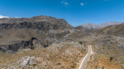 the complex serpentine of a mountain road in the mountains of Crete on a summer day shot from a drone
