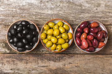 Green, black and red olives, olive oil on a brown wooden background. Fresh juicy olives in a bowl...