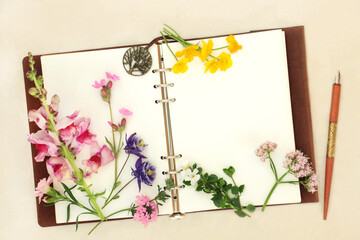 Flowers herbs and wildflowers with notebook and ink pen. Used in aromatherapy and natural herbal medicine for alternative remedies on hemp paper background.