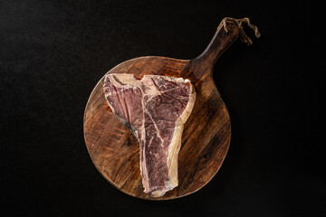 Siroy piece of beef meat T-bone, lies on a wooden board with spices. place for text, photon image....