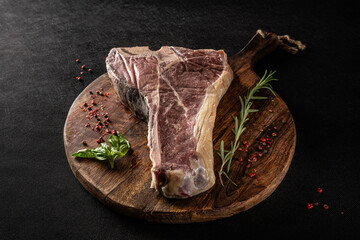 Siroy piece of beef meat T-bone, lies on a wooden board with spices. place for text, photon image....