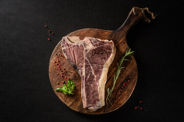 Siroy piece of beef meat T-bone, lies on a wooden board with spices. place for text, photon image....