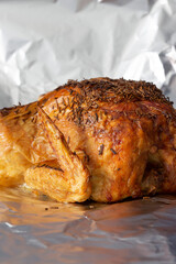 Whole roat chicken, covered in rosemary, on aluminium kitchen foil. Traditional Sunday roast concept