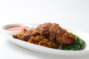 local wanton noodle mee in dark soy sauce with chicken chop cutlet, vegetables and chilli sauce in plate chopstick on white vintage newspaper background asian chef halal food restaurant banquet menu