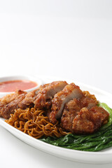 local wanton noodle mee in dark soy sauce with chicken chop cutlet, vegetables and chilli sauce in plate chopstick on white vintage newspaper background asian chef halal food restaurant banquet menu