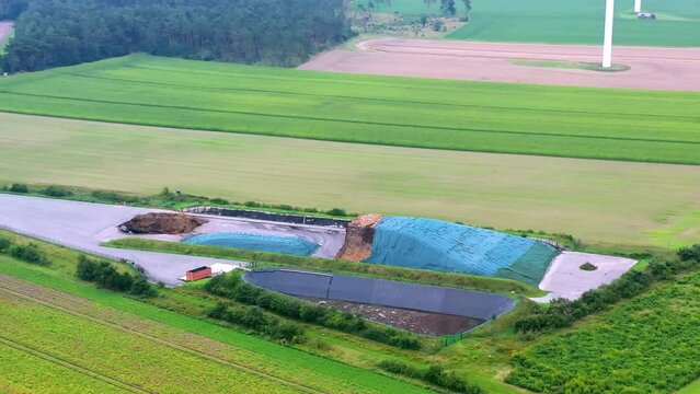 Aerial view of the silage windrow, a slurry tank and the bioenergy processing plant among green fields in Germany.