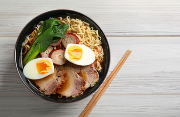 Bowl of delicious ramen with meat and egg on violet table, top view with space for text. Noodle soup