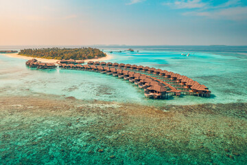 Sunset on Maldives island, luxury water villas resort and wooden pier. Beautiful aerial sky clouds...