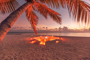 Romantic dinner in beach sunset. Candles with palm leaves and colorful sky and sea. Amazing coast...