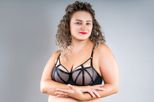 Curvy busty plus size model in push up bra on gray background, overweight woman in sexy lingerie, body positive concept