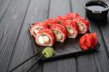 Sushi roll with caviar on a black background served on a stone board, top view