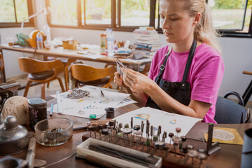 Young female jeweler making jewelry in workshop