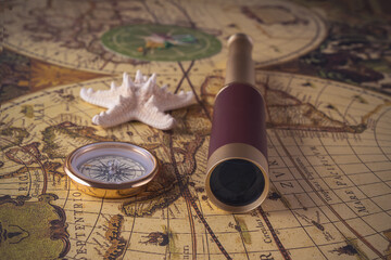 Spyglass, compass and starfish lie on a vintage map