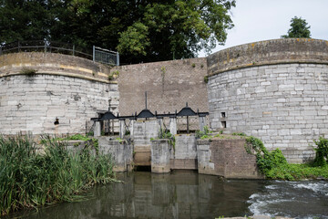 Fototapeta na wymiar water gate Waterpoort De Reek Stadsmuur Maastricht, Netherlands. Fortified historic medieval city walls with river Jeker in monseigneur nolenspark park. Old town protective defence stone structure 