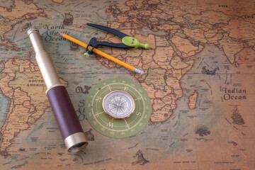 Spyglass, compass and a pencil with a measuring instrument lie on an old map. Copy space