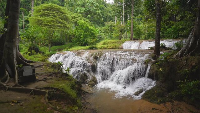 waterfall stream on nature clear slow motion water and green tree jungle in natural forest or rainforest at Kroeng Krawia waterfall in Thailand on rainy season for wild landscape background side view