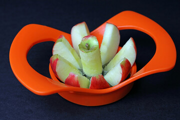 an apple being cut in to segments by an apple slicer.