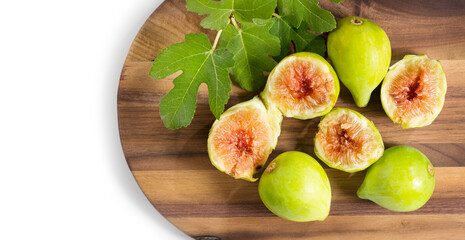 Fig fruits. Ripe sweet yellow and green figs fruit with leaves on wooden table close up, isolated on white background. Top view
