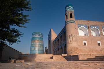 Old city view with iconic Kalta Minor minaret and ancient madrasah at sunset, Khiva, Uzbekistan