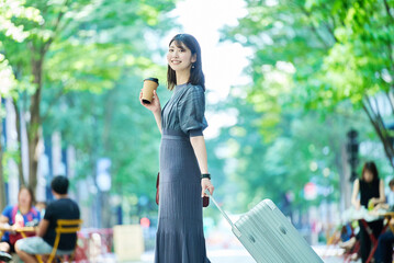 スーツケースを持って街を歩く女性