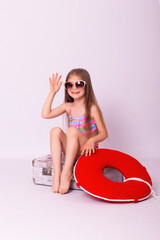 Young beauty little girl children sitting on retro suitcase. Smiling happy girl children wearing sunglasses.