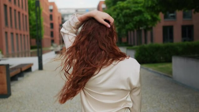 A Beautiful Red Haired Woman Walking In The Street, Turning Around And Looking Into The Camera. 