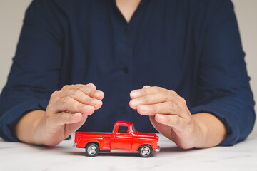 Auto Insurance concept. Businessman hands protection of a red car mockup on a table while sitting at the table