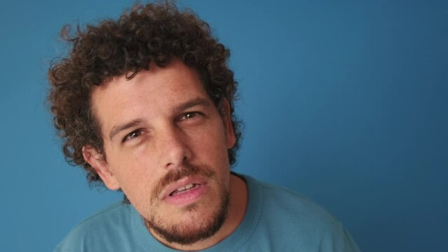 Close-up of man looking at the camera looking for something isolated on blue background
