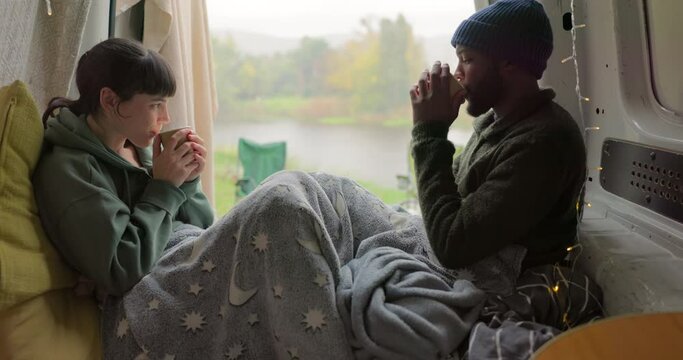 Camping, coffee and a couple in a car with a toast in the morning for a road trip and relax. Happy, interracial and a black man and woman in transport with tea during a vacation in the countryside